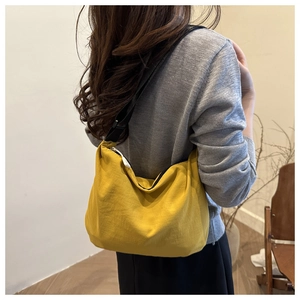 Detailed side view of a large yellow nylon crossbody bag with adjustable black shoulder strap