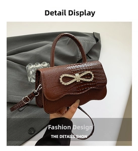 Detail of brown crocodile pattern handbag featuring a sparkling rhinestone bow buckle