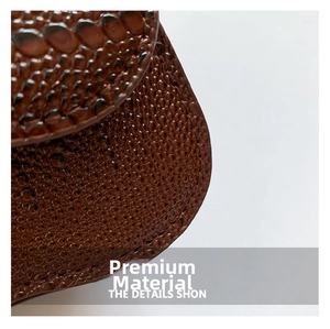 Detailed macro view of the premium brown crocodile pattern texture on a leather handbag