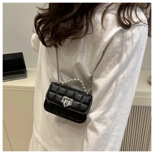 Close-up of black quilted mini bag with pearl handle and silver twist lock detail