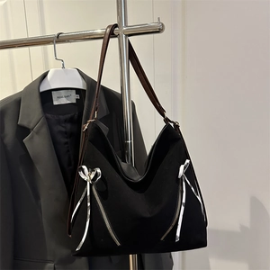 Large black canvas tote bag with metal zippers and brown leather straps on hanger