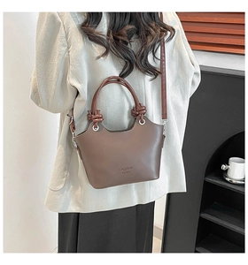 Close-up of brown leather bucket bag with knotted handle and fashion lettering