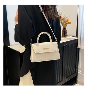 Détail du sac bandoulière crème avec poignée tissée en spirale et fermoir en métal doré