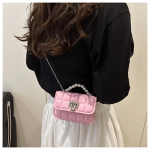 Detail view of pink quilted crossbody bag with pearl handle and metal chain on a model