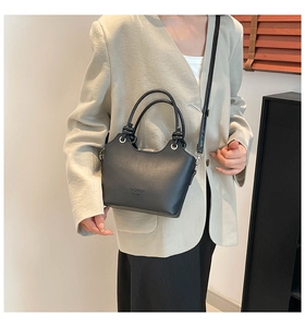 Detail of black faux leather bucket bag with knotted handle and silver metal hardware