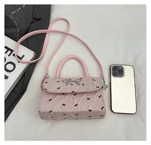 Vue détaillée du sac à nœud rose avec smartphone et livre pour comparer la taille