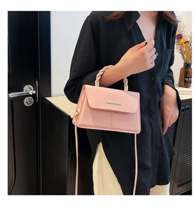 Sac à bandoulière rose avec poignée tressée et détail en métal doré sur un mannequin