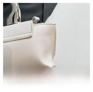 Detail of white PU leather bag featuring precise stitching and a metallic curved handle