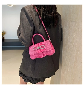 Detail of fuchsia wave edge bag featuring crocodile texture and rhinestone bow