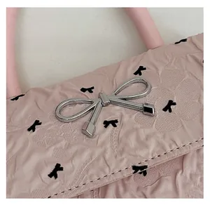 Gros plan sur le tissu texturé rose avec motifs nœuds noirs et boucle argentée en nœud