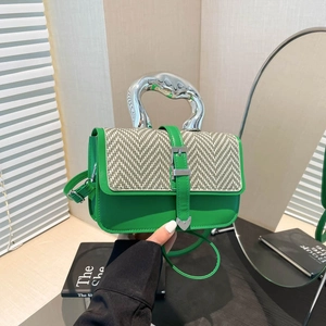Green houndstooth handbag with silver irregular handle and metal buckle shown in hand