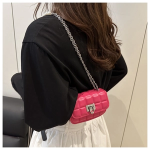 Detail of fuchsia quilted mini bag featuring a pearl-embellished silver chain strap