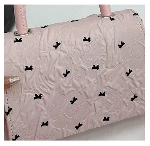 Détail du tissu froissé rose avec motifs nœuds noirs et boucles métalliques de fixation