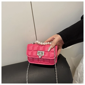 Detail of fuchsia quilted handbag with white pearl handle and silver chain strap