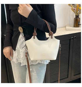 Detail view of white leather bucket bag with brown knotted handles and fashion text