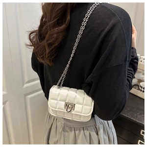 Side view of white quilted chain bag on shoulder featuring silver square metal lock