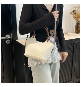 Detail of contrast stitch handle and shoulder strap on ivory PU leather crossbody bag