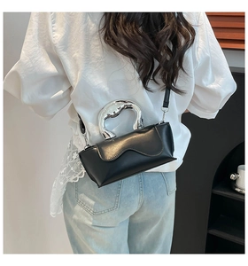 Close-up of black PU leather bag with wide silver metal handle and wave-shaped flap cover