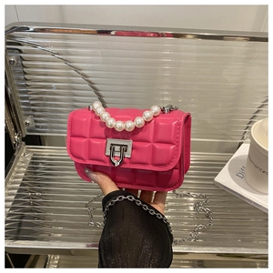 Detail of pink quilted crossbody bag featuring large pearl handle and silver metal chain