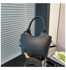 Detail of black bucket bag with cylindrical braided handle and silver metal hardware
