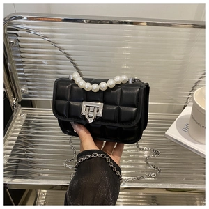Detail of black quilted mini bag featuring large pearl handle and silver chain strap