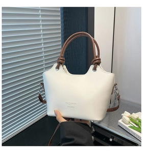 Detail of white bucket bag with brown knotted handle and Fashion H.C Bag logo engraving