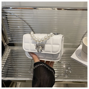 Detail of white quilted crossbody bag with pearl handle and silver chain strap