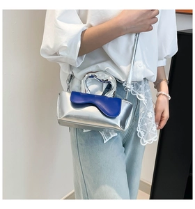 Detail of a chic color-block mini bag with a bold silver handle and blue flap