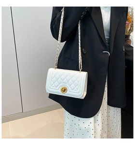 Close-up of quilted pattern and gold metal chain strap on the white crossbody bag