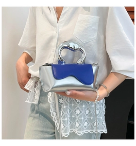 Detail of silver metallic dumpling bag with blue wavy flap and curved metal handle