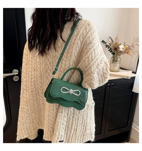 Detail of green crocodile texture handbag with sparkling bow buckle and top handle