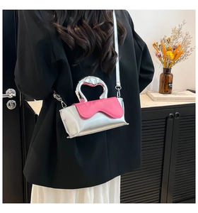 Detail of silver metallic handbag with pink wavy trim and heart-shaped handle