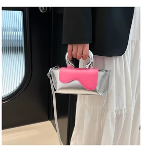 Detail of silver metallic handle and pink wavy flap on a modern crossbody bag