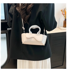 Detail view of a white minimalist PU leather crossbody bag with silver curved handle