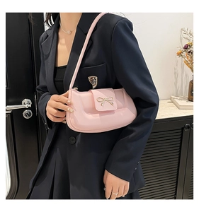 Detail of pink bow-knot shoulder bag with metallic buckle worn with black blazer