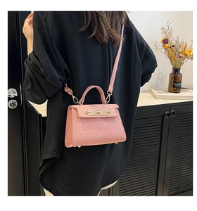 Detailed view of pink trapezoid handbag with crocodile texture and metallic turn-lock closure
