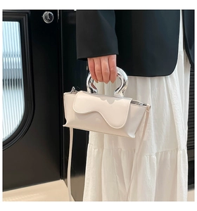 Chic cream mini square bag with wavy flap and silver metal handle carried by model