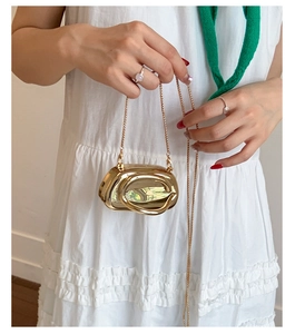 Close-up of golden mirror shell clutch with circular handle and fine metal chain