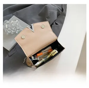 Detail of beige crossbody bag showing interior capacity with lipstick and perfume