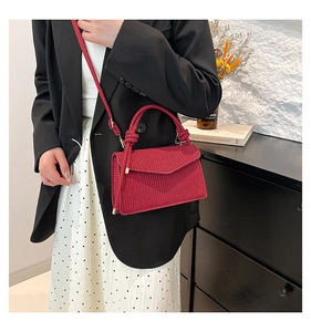 Detail of red woven texture crossbody bag with unique knot handle on a model