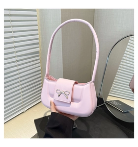 Detail of light pink shoulder bag with elegant gold metal bow buckle and smooth leather
