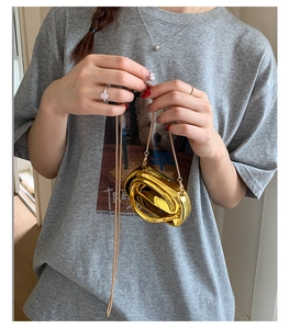 Detailed close-up of a mini gold metallic mirror clutch bag with fine chain strap on model