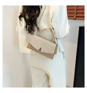 Detail of champagne sequined crossbody bag with silver V-clasp and delicate chain strap