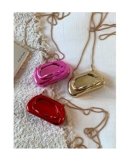 Close-up of metallic sculptural mini bags in gold red and pink with gold chain straps