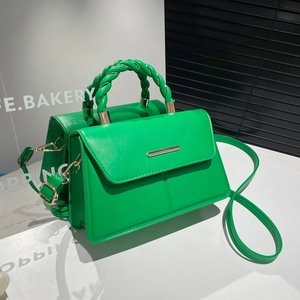 Sac à rabat vert chic avec poignée tressée et détails dorés dans un studio moderne
