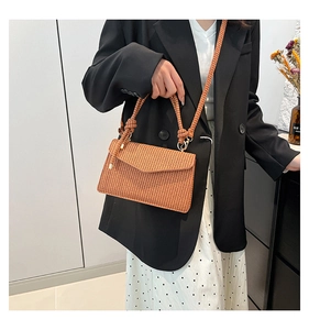 Detail of hand-woven crossbody bag with caramel brown fiber texture and knot accents
