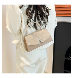 Detail of glitter patchwork handbag with silver V-clasp and chain strap on model