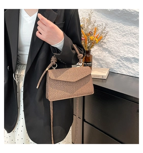 Detail of brown striped weave texture on crossbody bag with knotted handle and flap cover