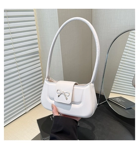 Close-up of a white PU leather shoulder bag featuring a decorative silver metal bow detail