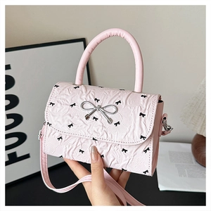 Détail d'un sac à main rose à nœuds avec texture plissée et boucle argentée